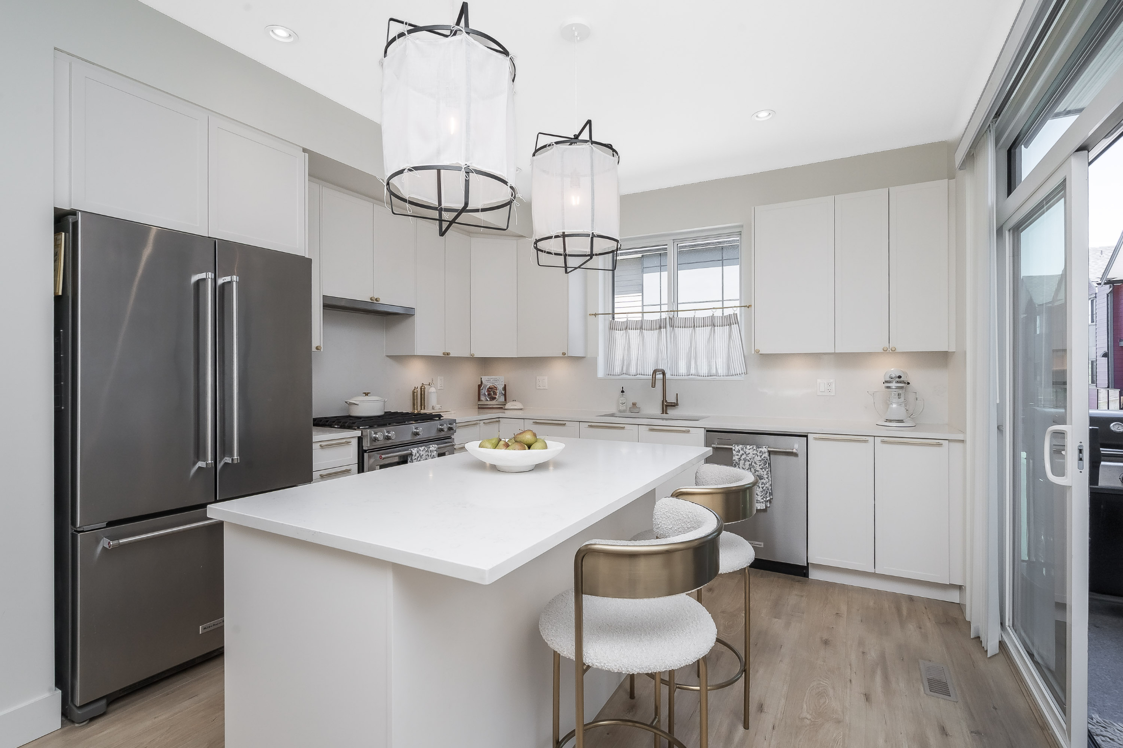 Bright kitchen with white cabinetry, center island and pendant lights in Willoughby townhome.