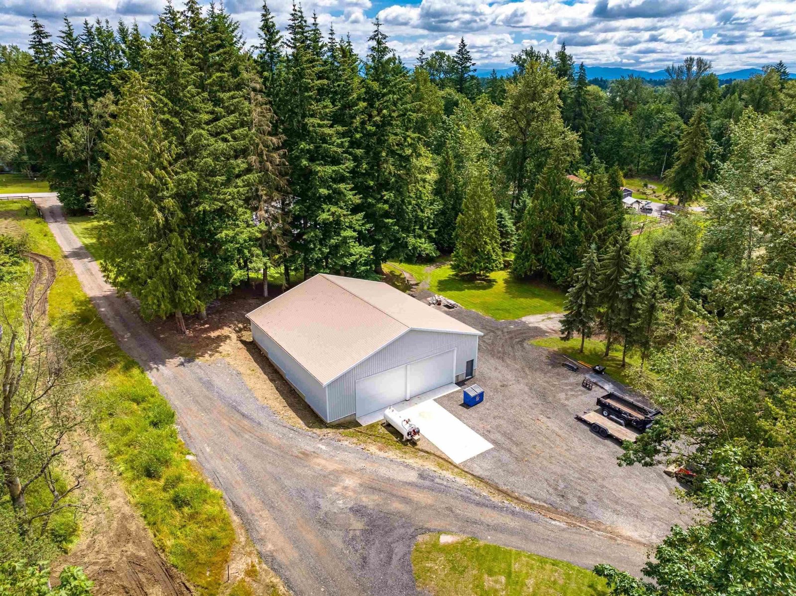 Aerial view of a treed five-acre South Langley property with a large detached shop and long driveway