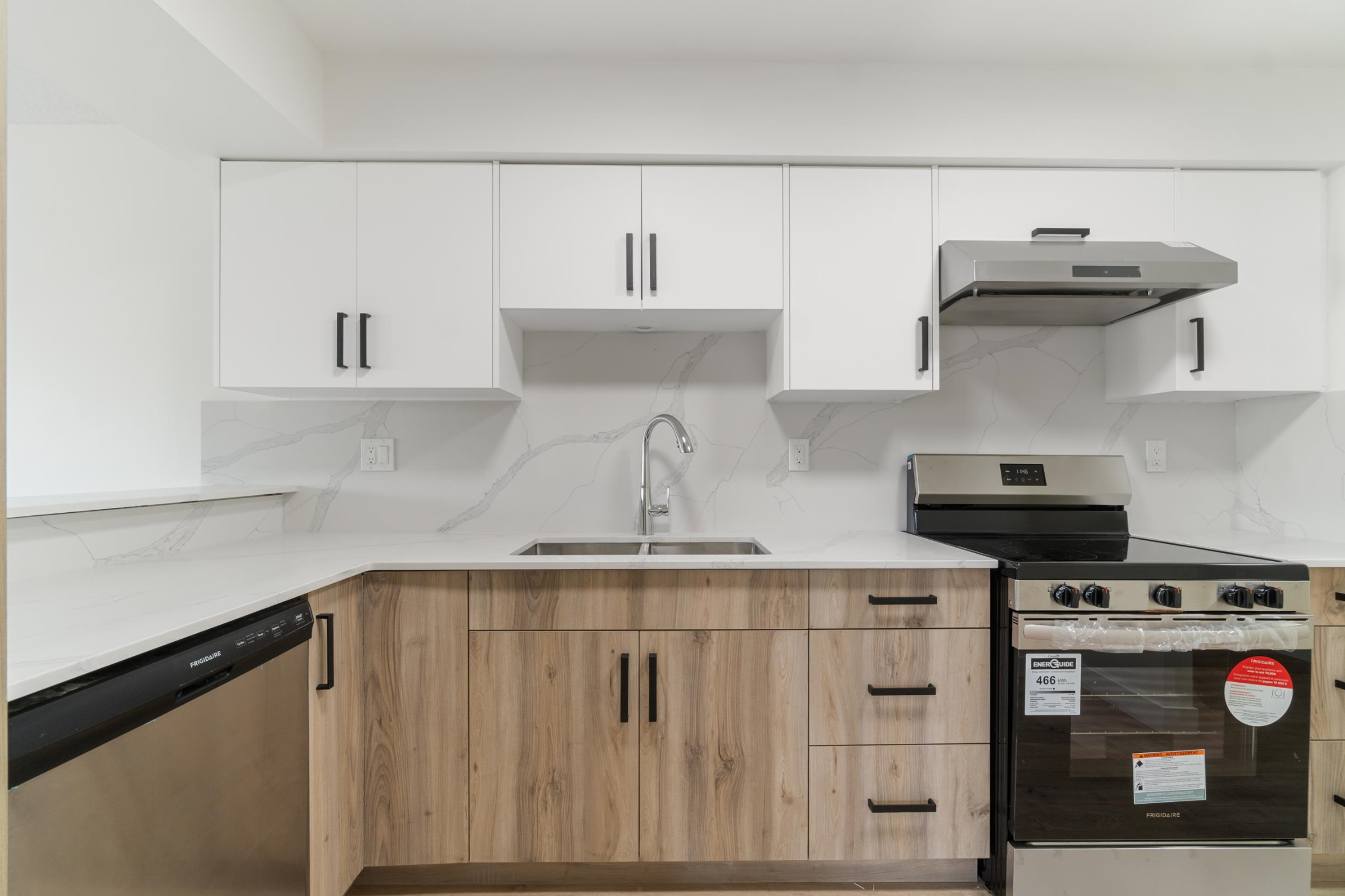 Kitchen with a sink, decorative backsplash, under cabinet range hood, and stainless steel appliances