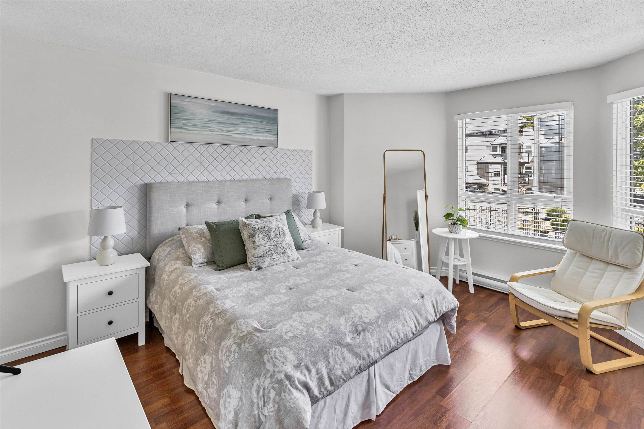 Bright bedroom with large windows and neutral decor.