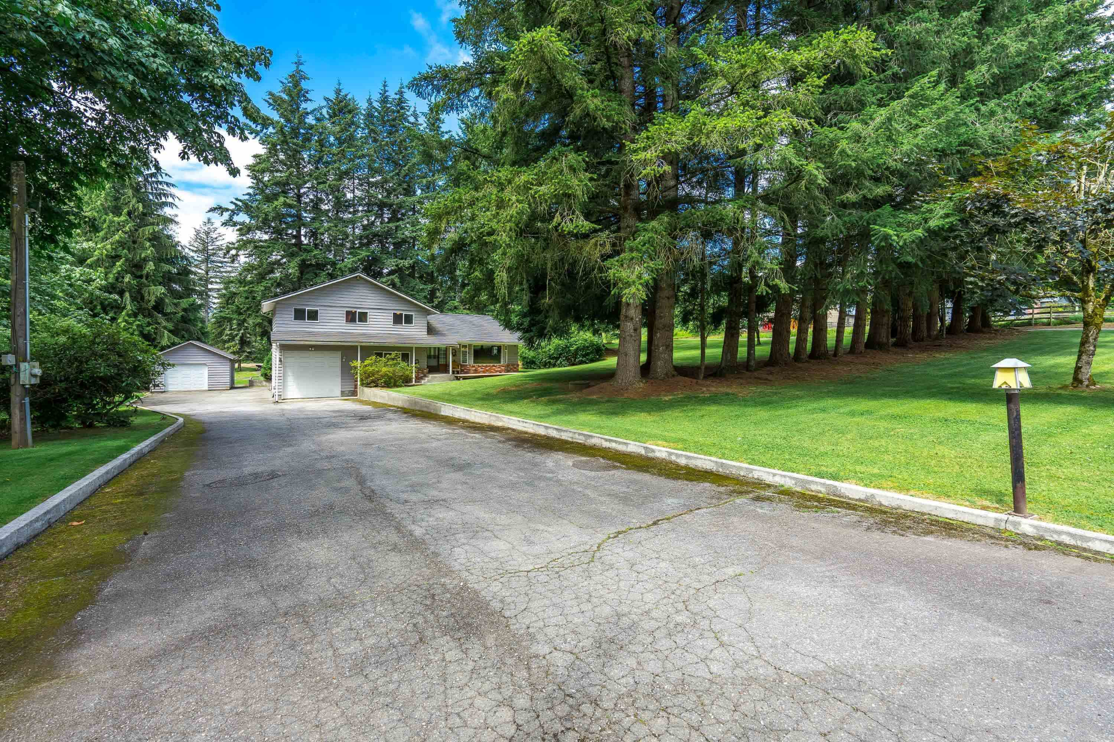 Large driveway leading to charming country-style house.